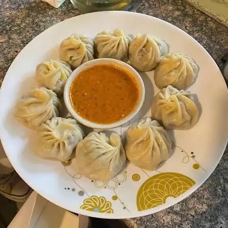 Plate of fresh steamed buff momo dumplings with dipping sauce