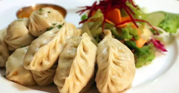 Plate of fresh veg momo dumplings with dipping sauce